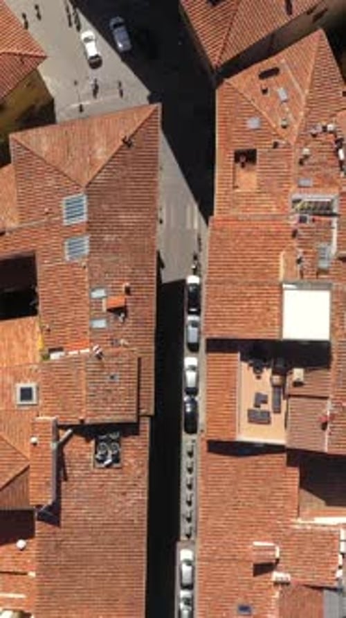 Vertical top down view flying above roofs, roads and city on a sunny day in Florence in Italy.