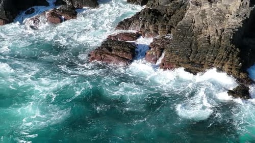 Aerial Footage of Turquoise Ocean Waters Washing Rugged Rocky Shoreline