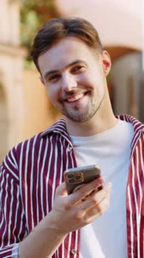 Smiling Man Looking at Phone Outside in Vertical Video