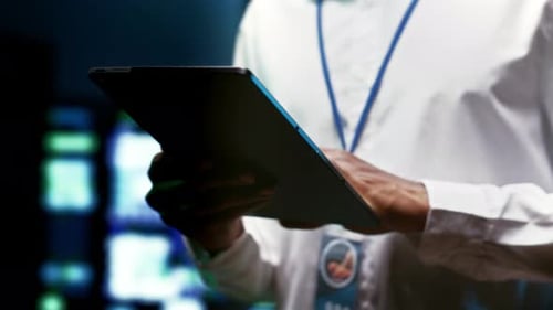 Person Using Tablet in Dark Tech Control Room