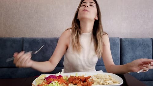 Slow motion:Beautiful young girl eats chicken food with a big enjoy in a restaurant or cafe while si