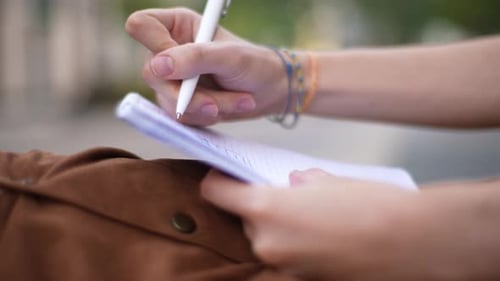Close-up of Hand Writing in Notebook