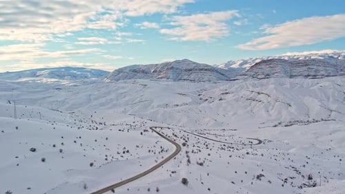 Aerial View of Snow-Covered Mountain Road in Winter Landscape
