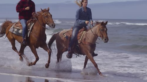 Women enjoying horseback riding along a beautiful beach coastline in slow motion