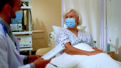Doctor Consults Elderly Patient in Hospital Room