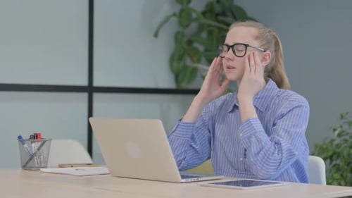 Junge Frau mit Kopfschmerzen arbeitet am Laptop