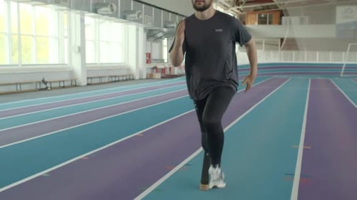 Determined Man Running with Prosthetic Leg on Track
