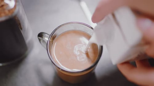 Close Up Of Dairy Milk Pouring Into Hot Coffee Glass Mug