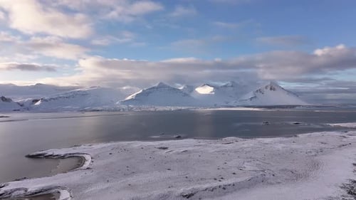 Snowy Iceland mountains and arctic coastline with calm water - aerial winter landscape