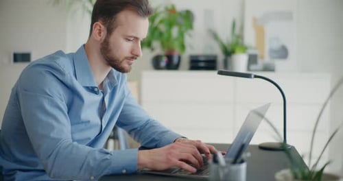 Young Man Working on Laptop at Desk