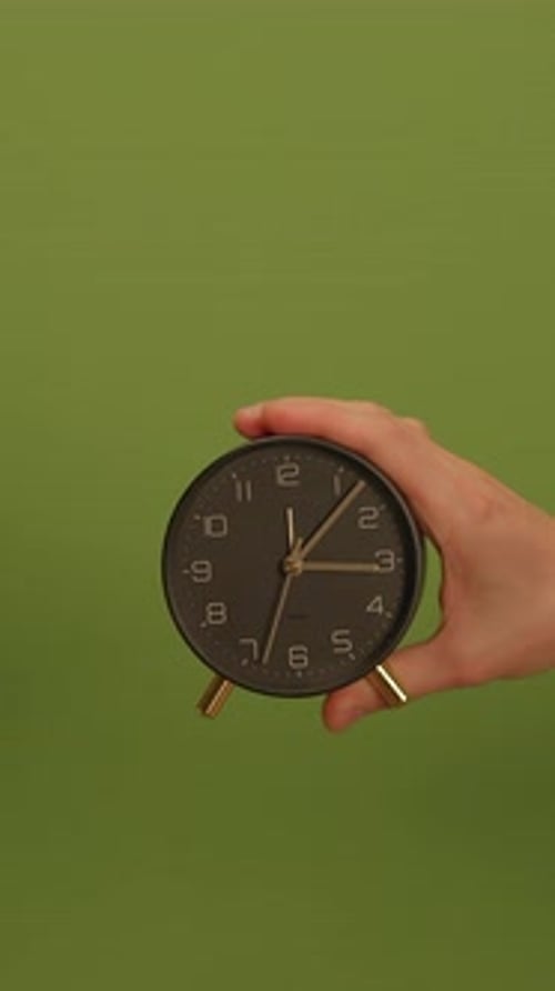 An Elegant Clock Handheld Displayed Beautifully Against a Green Background Setting