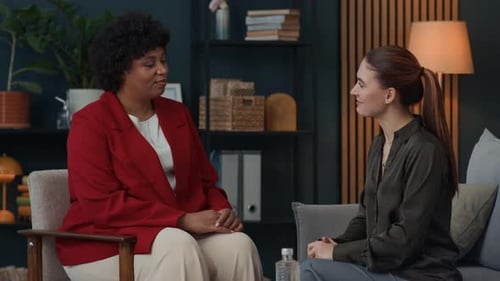 Two Women Talking and Shaking Hands Indoors
