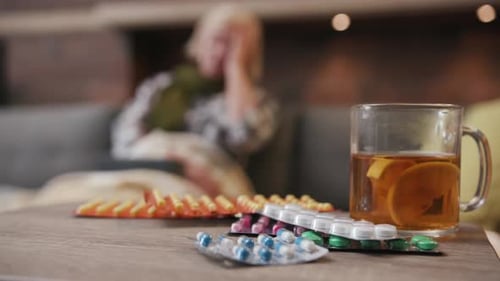 Close Up of Many Different Spinning Drugs Older Woman Drink Tea Lying on Sofa Fever in Home Feel