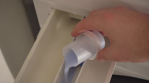Close-up: Laundry softener is poured into washing machine dispenser
