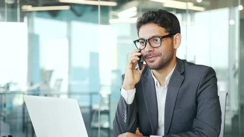 Enthusiastic Businessman Talking on Mobile Phone in Office