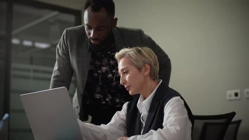 Professionals Discussing Business on Laptop in Modern Office
