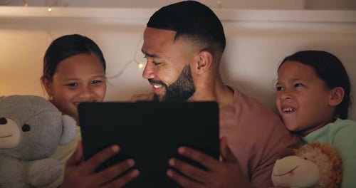 Father and Daughters Watching Tablet in Bed