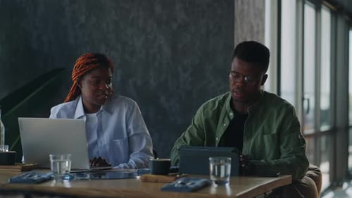 Black Man and Woman Having Business Negotiations While Sipping Coffee From Cups in a Coffee Shop