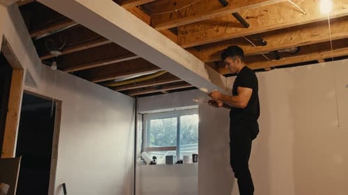 Young Adult Sanding Wall During Home Renovation