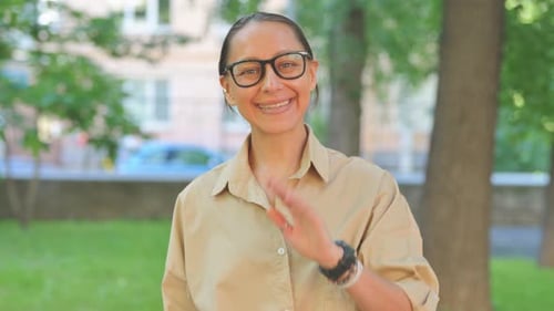 Smiling Woman Waving in City Park