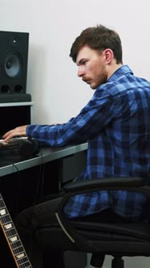 Male musician playing on midi piano keyboard at home music studio.Vertical video