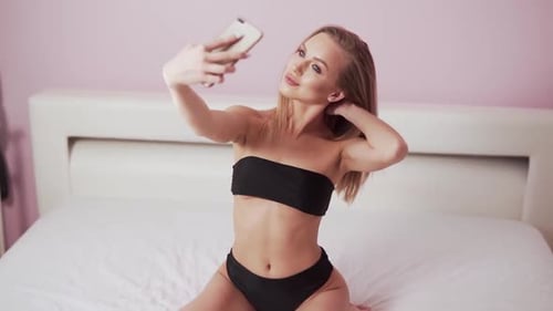Woman Taking Selfie on Bed in Bedroom