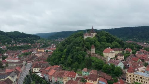 Una ciudad medieval con un castillo en una colina verde, vista aérea