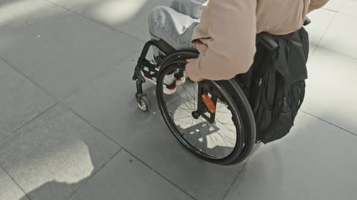 Man Riding Manual Wheelchair along Urban Street