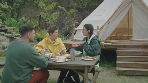 Friends Enjoying Breakfast While Camping Outdoors