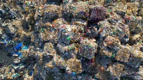 Drone view of huge heaps of pressed garbage at waste sorting plant. Slow motion