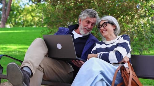 Happy Senior Couple Relaxing with Laptop in Park
