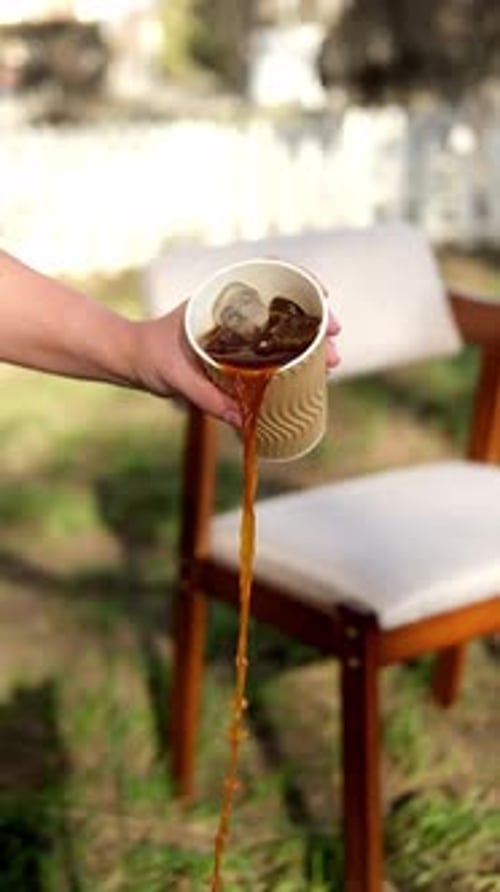 Footage of Iced Coffee Pouring Out of a Paper Cup on the Street