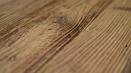 Vidéo de haute qualité montrant une surface en bois en gros plan avec un grain riche, une lumière chaude et une texture subtile