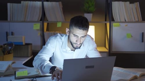Man Working on Laptop in Office at Night