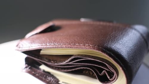Close Up of a Brown Wallet with Dollar Bills on a Black Background