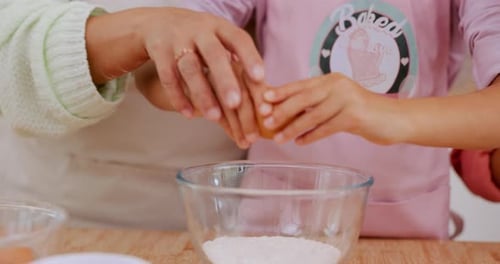 Adult and Child Cracking Egg into Bowl