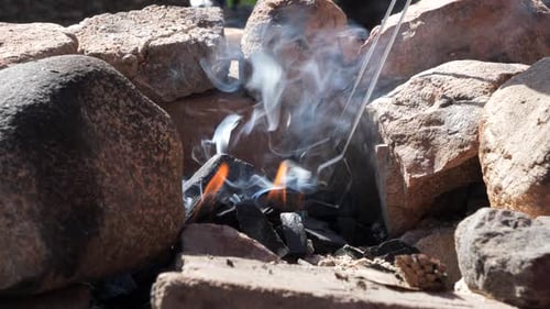 Charcoal Burning in Stone Fire Pit with Tongs