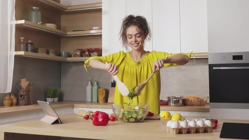 Young Adult Woman Making a Salad in Bright Kitchen