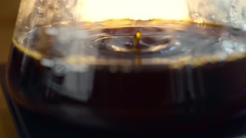 Coffee water brewed from the V60 drips into a glass container, slow motion and close-up shot.