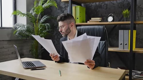Nervous Man Looks Through Documents and Throws Papers Away