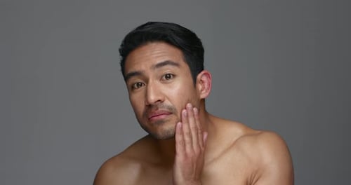 Asian man, face and skincare for grooming, hygiene or facial treatment against a grey studio