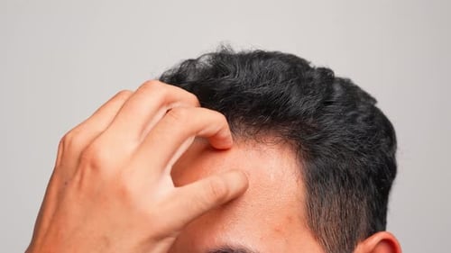 Man Examines Hair and Scalp Indoors