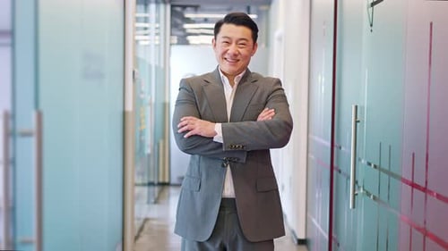 Joyful Male Standing Confidently with Arms Crossed in Corporate Office