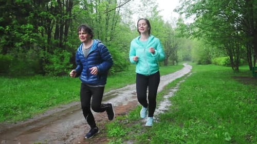 Sportive young people running. Couple run in the park during rainy day