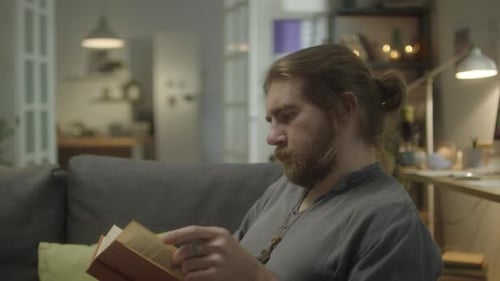Man Reading Book on Couch in Cozy Home