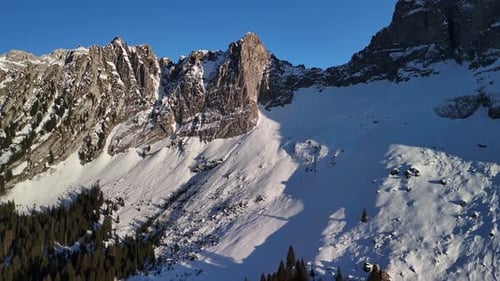 Dramatic Winter Mountains Sunlit Snow and Rugged Alpine Rock Face