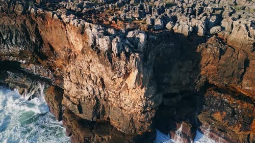 Rough cliffs scenery washing by foamy stormy waves aerial view
