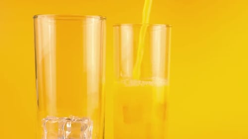 Chilled Orange Juice Pouring into Glass with Ice