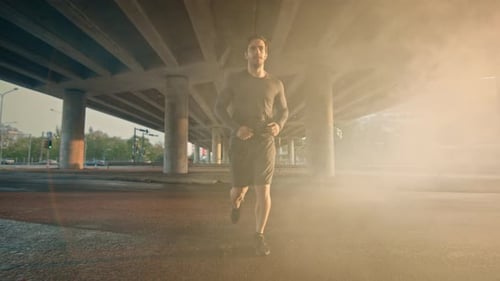 Athletic Muscular Young Man in Sports Outfit Jogging in a Street Filled With Steam. He is Running i