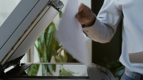 Anonymous Black Man Scanning Documents in Photocopier Machine in Office